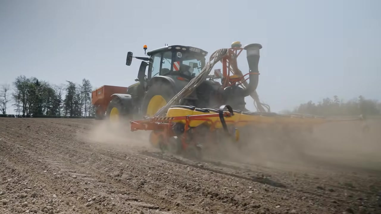 John Deere 6R mit Väderstad Tempo Maisdrille bei der Aussaat — Staubwolke am Feld