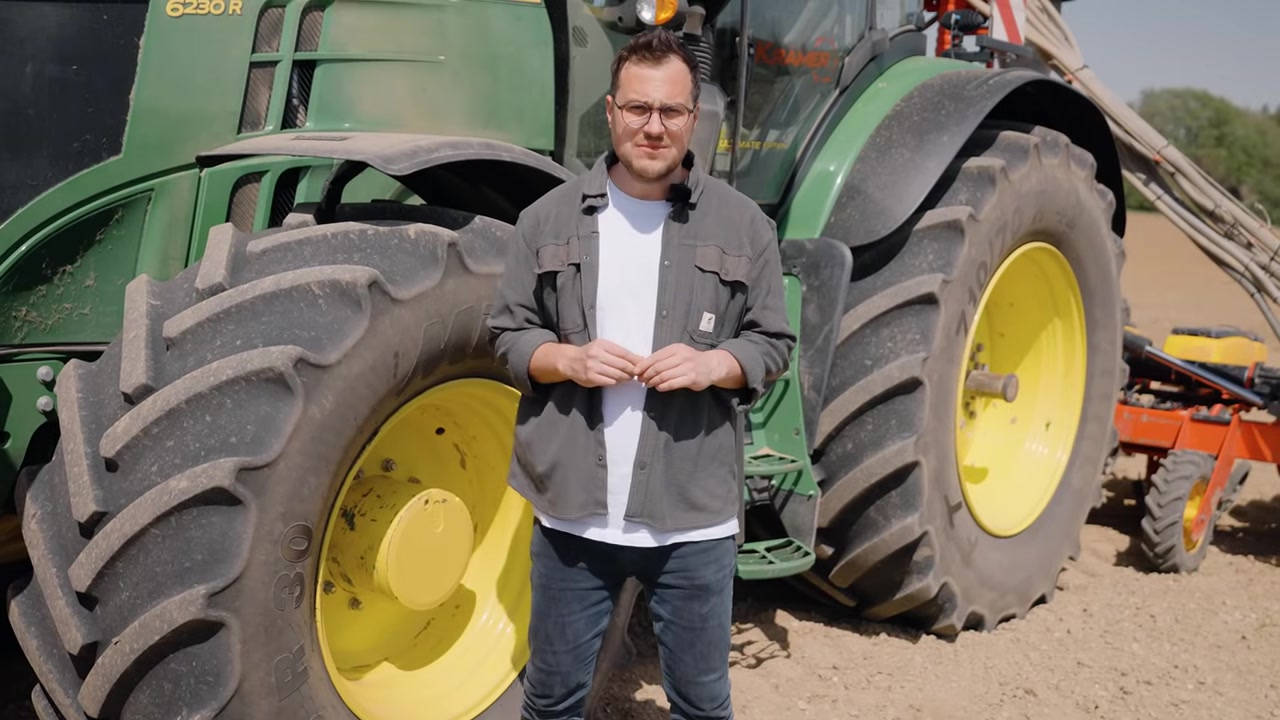 Moderator vor dem John Deere 6230R — Intro-Shot der Reportage